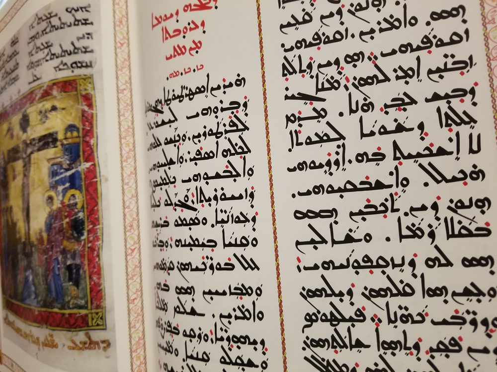 Close-up of a Gospel Lectionary page with handwritten Syriac text and an illuminated crucifixion scene